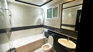 Uma casa de banho moderna com banheira, sanita e lavatório.