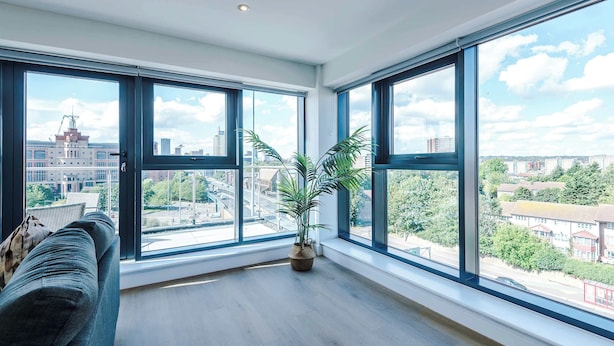 A spacious room with large windows, a wooden floor, and a potted plant. - Premium City Penthouse Ideal For Business (Leeds)