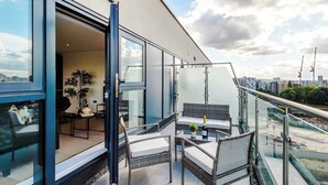 A balcony with wicker furniture, a glass door, and a view of the cityscape. - Premium City Penthouse Ideal For Business (Leeds)