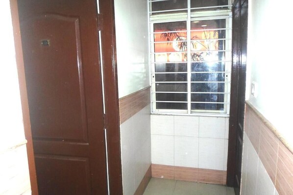 A narrow hallway with a door on the left and a window with metal bars on the right.