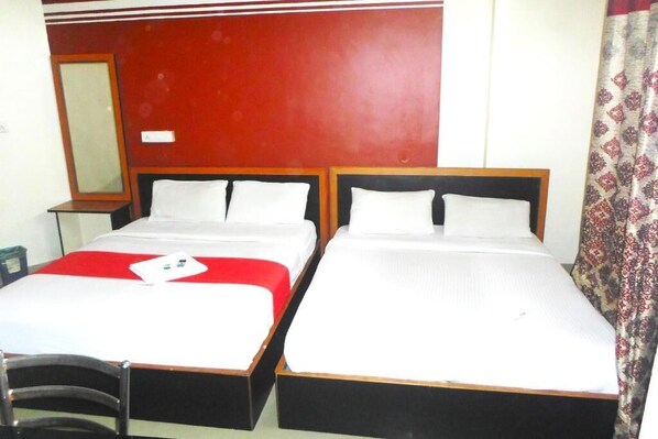 A hotel room with two single beds, a wooden headboard, a mirror, and a patterned curtain. - King Residency (Bengaluru)