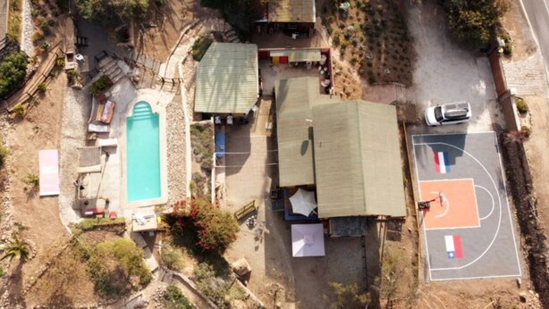 An aerial view of a residential property with a swimming pool, a basketball court, and a fenced yard. - Buho Cabin Studio BBQ Kitchen Parking Pool (La Serena)