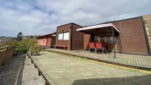A wooden deck with a covered outdoor seating area and a building with a large window. - Buho Cabin Studio BBQ Kitchen Parking Pool (La Serena)