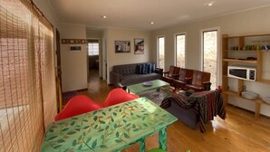 A spacious living area with a sofa, a dining table, and a kitchen area with a microwave. - Buho Cabin Studio BBQ Kitchen Parking Pool (La Serena)