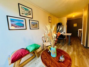 A dining area with a wooden table, chairs, and a vase with dried plants. There are framed pictures on the wall. - Buho Urban Curic A C Washer Dryer Wifi (Santiago)