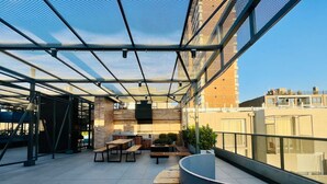 A rooftop terrace with a modern design, featuring a seating area with benches and tables, a grill, and potted plants. - Buho Urban Curic A C Washer Dryer Wifi (Santiago)