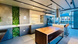 A modern kitchen with a wooden island, built-in greenery, and a view of the city through large windows. - Buho Urban Curic A C Washer Dryer Wifi (Santiago)