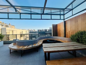 A rooftop terrace with a curved bench, a table, and a view of the cityscape. - Buho Urban Curic A C Washer Dryer Wifi (Santiago)
