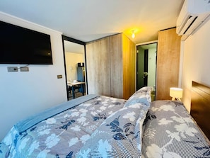 A hotel room with a bed, a desk, a chair, a mirror, and an air conditioning unit. - Buho Urban Curic A C Washer Dryer Wifi (Santiago)