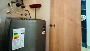 A water heater with a label indicating energy efficiency, a red broom, and a wooden door. - Buho Urban Curic A C Washer Dryer Wifi (Santiago)