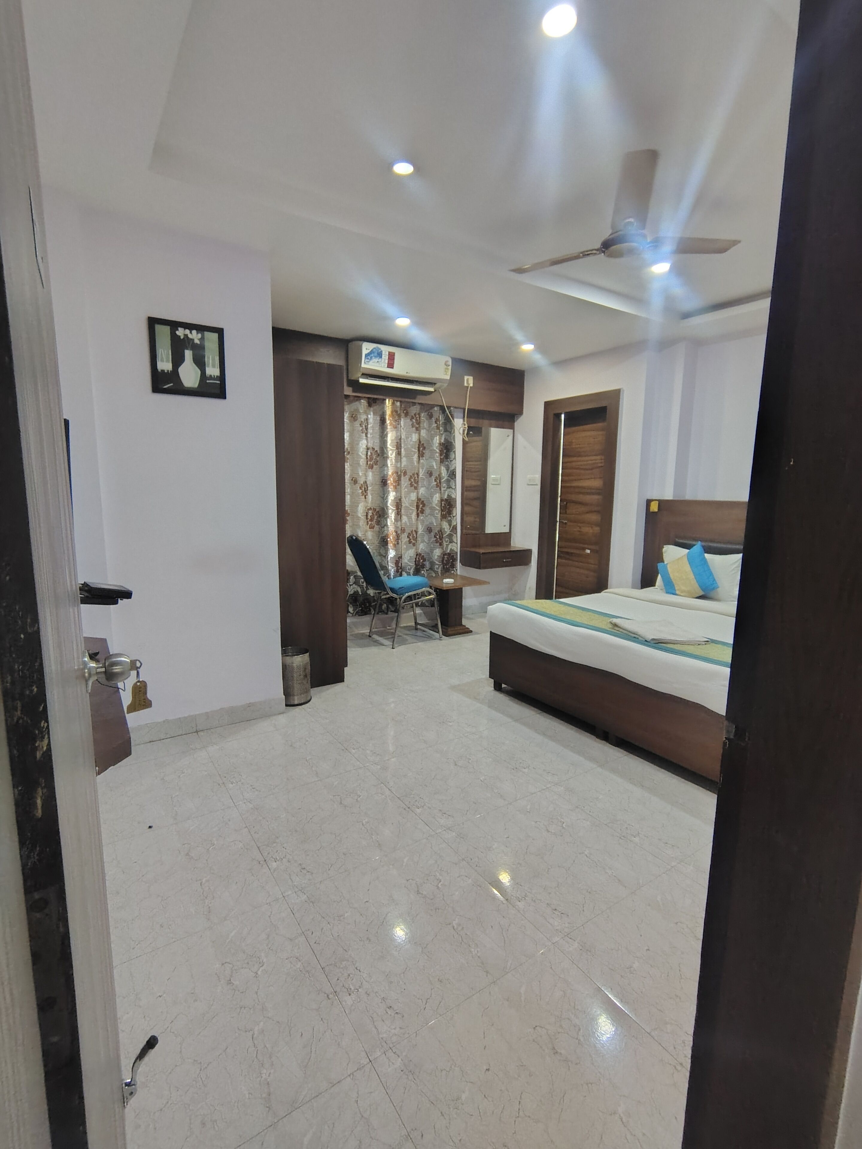 Une chambre avec un lit, un ventilateur de plafond, un appareil de climatisation, une chaise et une petite table.