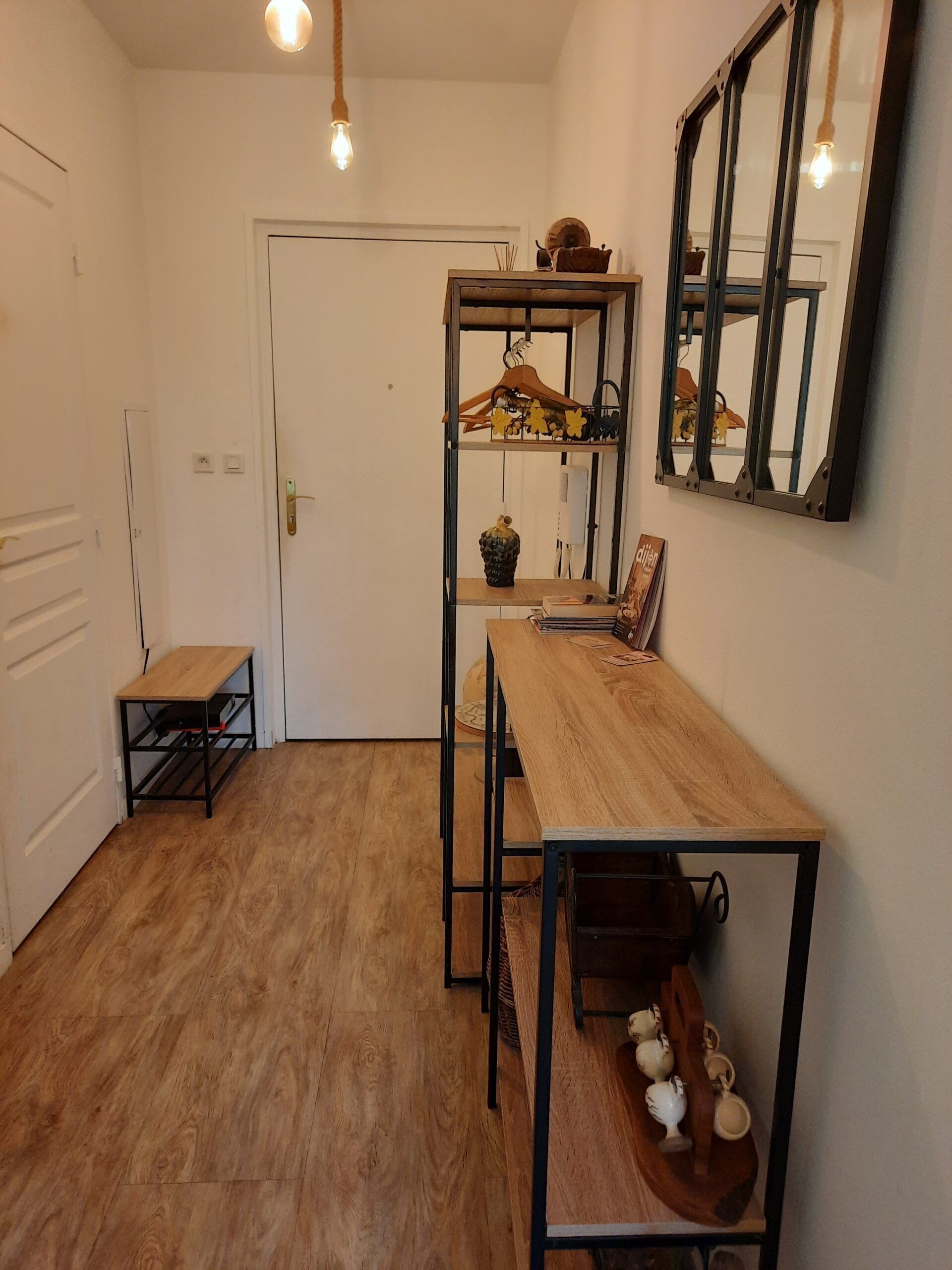 Een kleine keuken met een houten tafel, een hanglamp en een spiegel aan de muur.