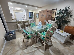 A dining area with a glass table, wicker chairs, and a potted plant. - Vacation in the picturesque, waterfront Isla Del Sol community of Bahia (St. Petersburg)