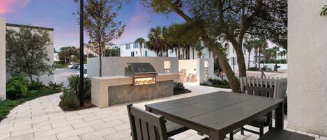 An outdoor patio with a grill, seating, and a view of the street.