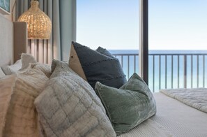 Ein Bett mit Kissen, eine Hängelampe und Meerblick.