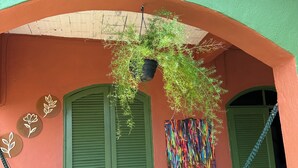A building with a green archway, a hammock, and hanging plants.