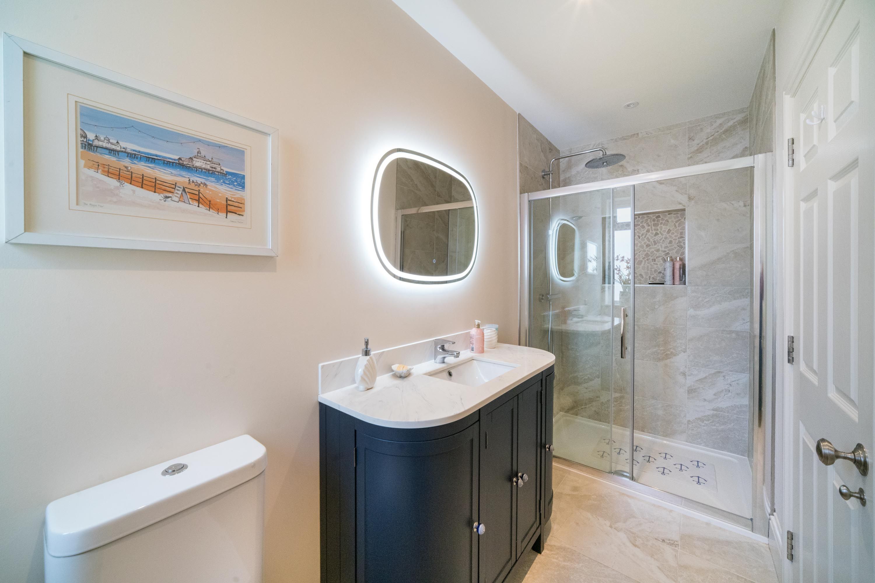 Un baño moderno con inodoro, tocador con espejo y ducha envuelta en vidrio.