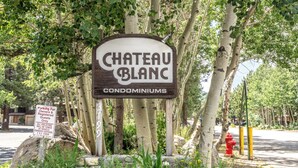 Een bordje voor appartementencomplex Chateau Blanc, omringd door bomen en groen.