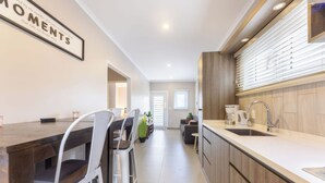Une cuisine moderne dotée d’un plan de travail en bois, d’un évier et d’un coin repas avec des chaises et une table.