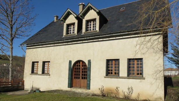 Una casa a due piani con un tetto spiovente, una porta verde e numerose finestre.