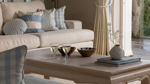 A cozy living room with a sofa, coffee table, and decorative items. - Springtide - New Polzeath - stylish sea view property sleeping 8-9 guests (New Polzeath)