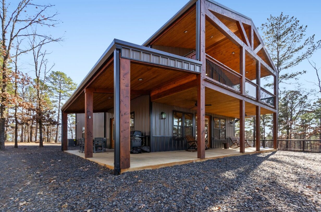 A two-story wooden cabin with a covered porch and a balcony.