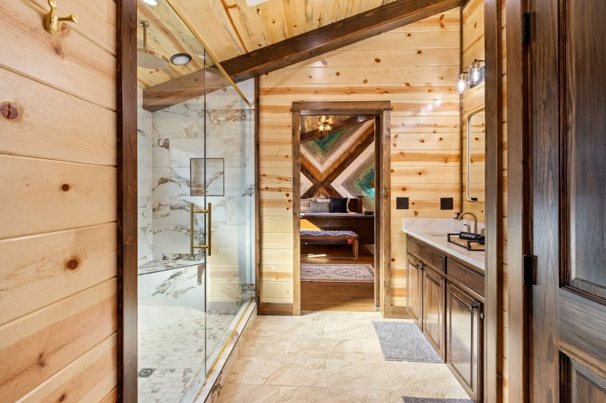 A wooden interior with a glass shower, a marble-tiled wall, and a wooden bench.