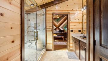 A wooden interior with a glass shower, a marble-tiled wall, and a wooden bench.
