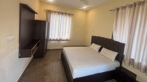 A bedroom with a bed, a wardrobe, a ceiling fan, and curtains. - Eco Fort Resort (Mahwah)