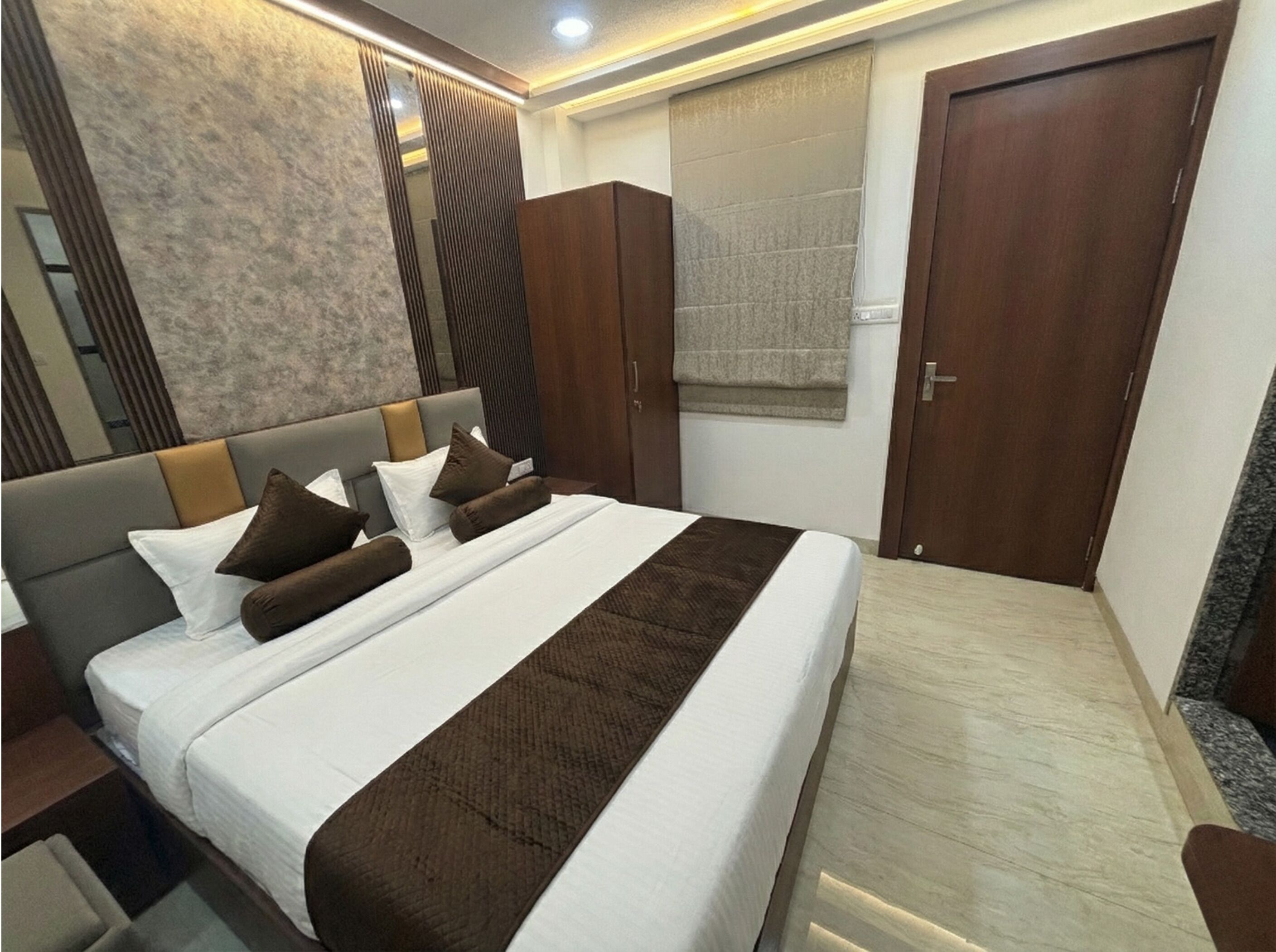 A modern bedroom with a large bed, a nightstand, a wardrobe, and a bathroom with a towel hanging.
