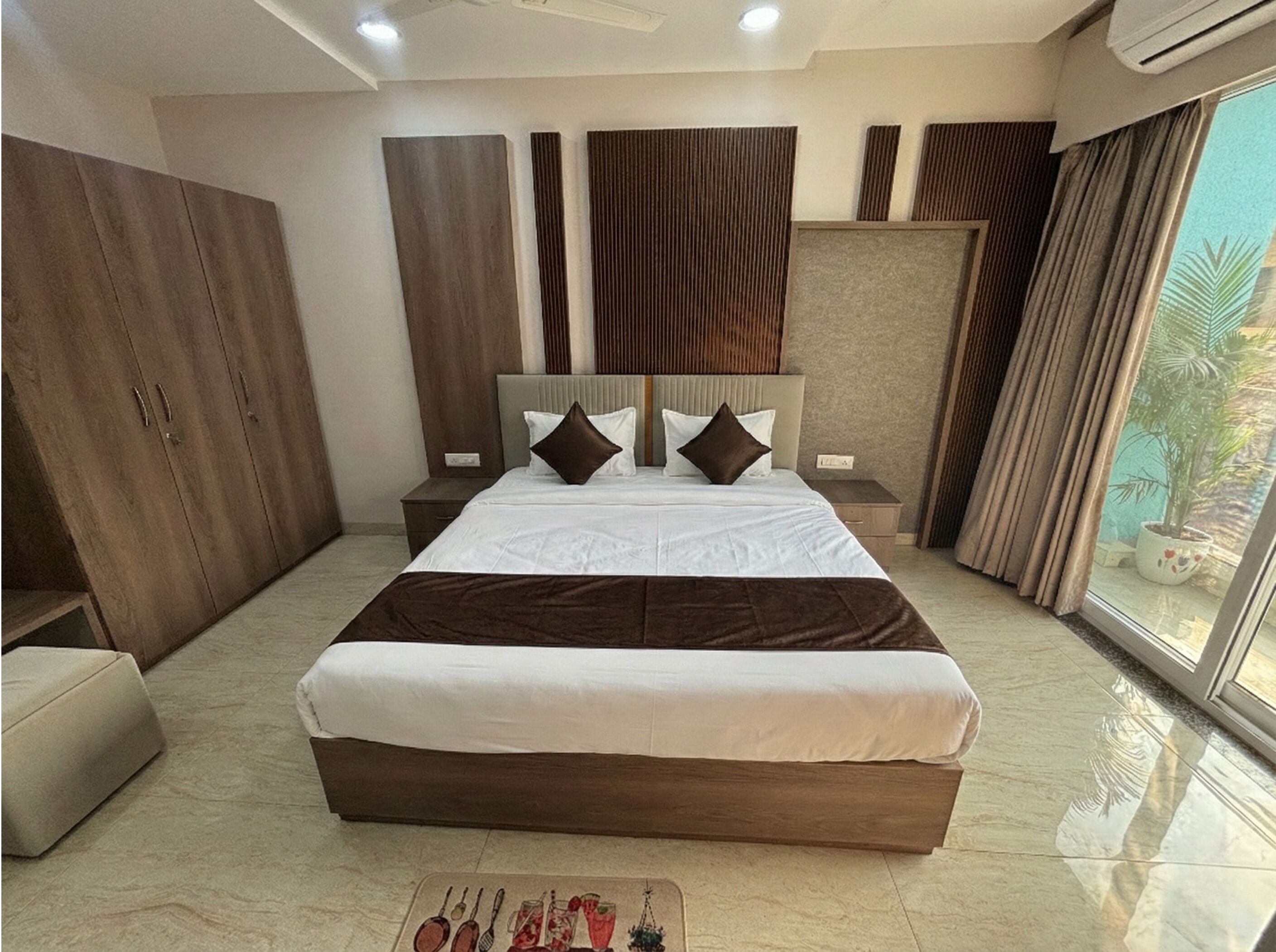 A modern bedroom with a large bed, wooden wardrobe, and a view of the outdoors.