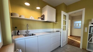 A kitchen with white cabinets, a stainless steel sink, and a microwave. - 30s charm in a central location (Ludwigsburg)