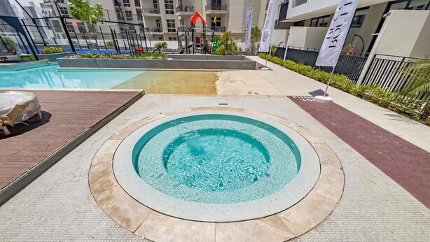 A circular hot tub with a tiled floor, surrounded by a low wall. A sign indicates the hot tub's diameter as 0.90m. - Modern and Budget friendly studio Apartment with Gym, Pool and Paddle court (Dubai)