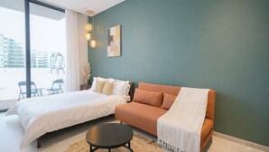 A modern bedroom with a bed, a sofa, and a small table. - Modern and Budget friendly studio Apartment with Gym, Pool and Paddle court (Dubai)