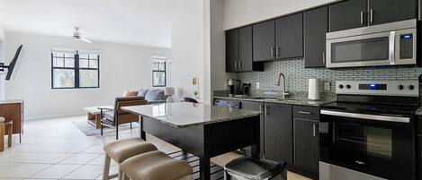 A modern kitchen with a central island, stainless steel appliances, and a dining area with a sofa and chairs.