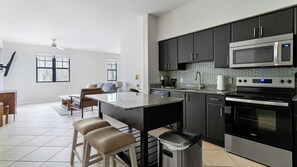 A modern kitchen with a central island, stainless steel appliances, and a dining area with a sofa and chairs.