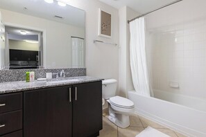 A bathroom with a sink, toilet, and shower. - Landing Furnished Apartments at Miramar Town Center (Miramar)