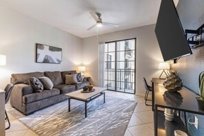A modern living room with a grey sofa, a coffee table, and a TV on a stand. - Landing Furnished Apartments at Miramar Town Center (Miramar)
