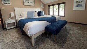 Une chambre à coucher avec un grand lit, une table de chevet, une fenêtre et des œuvres d’art murales.
