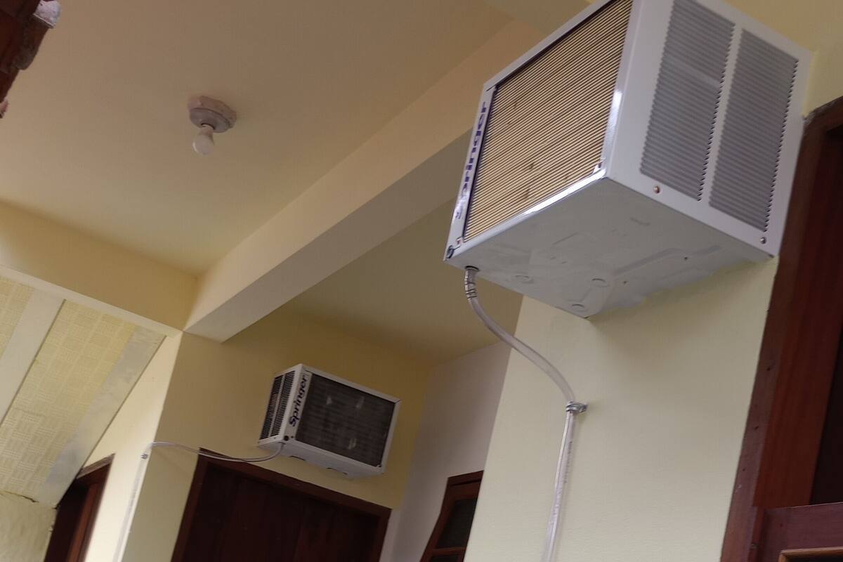 A building exterior with a door, a window, and an air conditioning unit mounted on the wall.