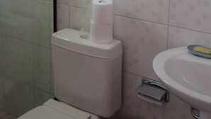 Un baño con inodoro, lavamanos y zona de ducha.