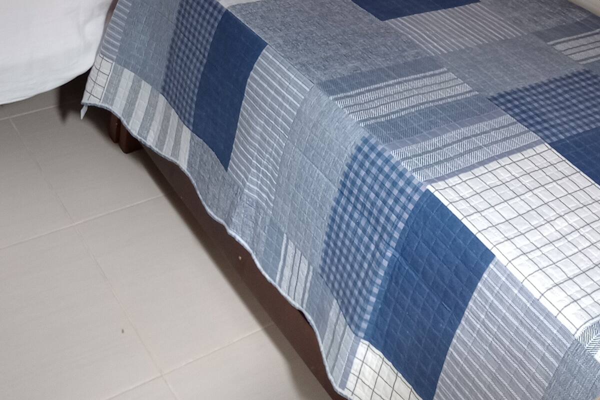 A single bed with a wooden frame and a quilt.