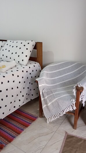 A bed with a polka dot bedspread, a white throw blanket, and a colorful woven rug. - Hospedagem Pouso Famíliar  (Paraty)