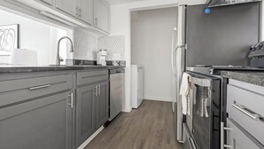 Eine moderne Küche mit grauen Schränken, einem Edelstahlkühlschrank und einem Geschirrspüler.
