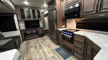 A compact kitchen with wooden cabinets, a stainless steel refrigerator, and a microwave.