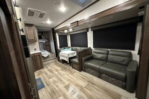 Un intérieur de camping-car compact comprenant un coin cuisine, un espace salon avec un canapé et une table.