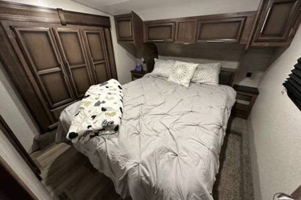 Une chambre à coucher avec un lit, une tête de lit en bois et une table de chevet avec une lampe.