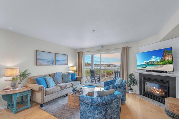 Unwind in this bright coastal living room with ocean views, cozy fireplace, and beachy decor perfect for your seaside retreat. - Siletz Bay Condo: Ground-Level View, Beach Path & Nearby Dining (Lincoln City)