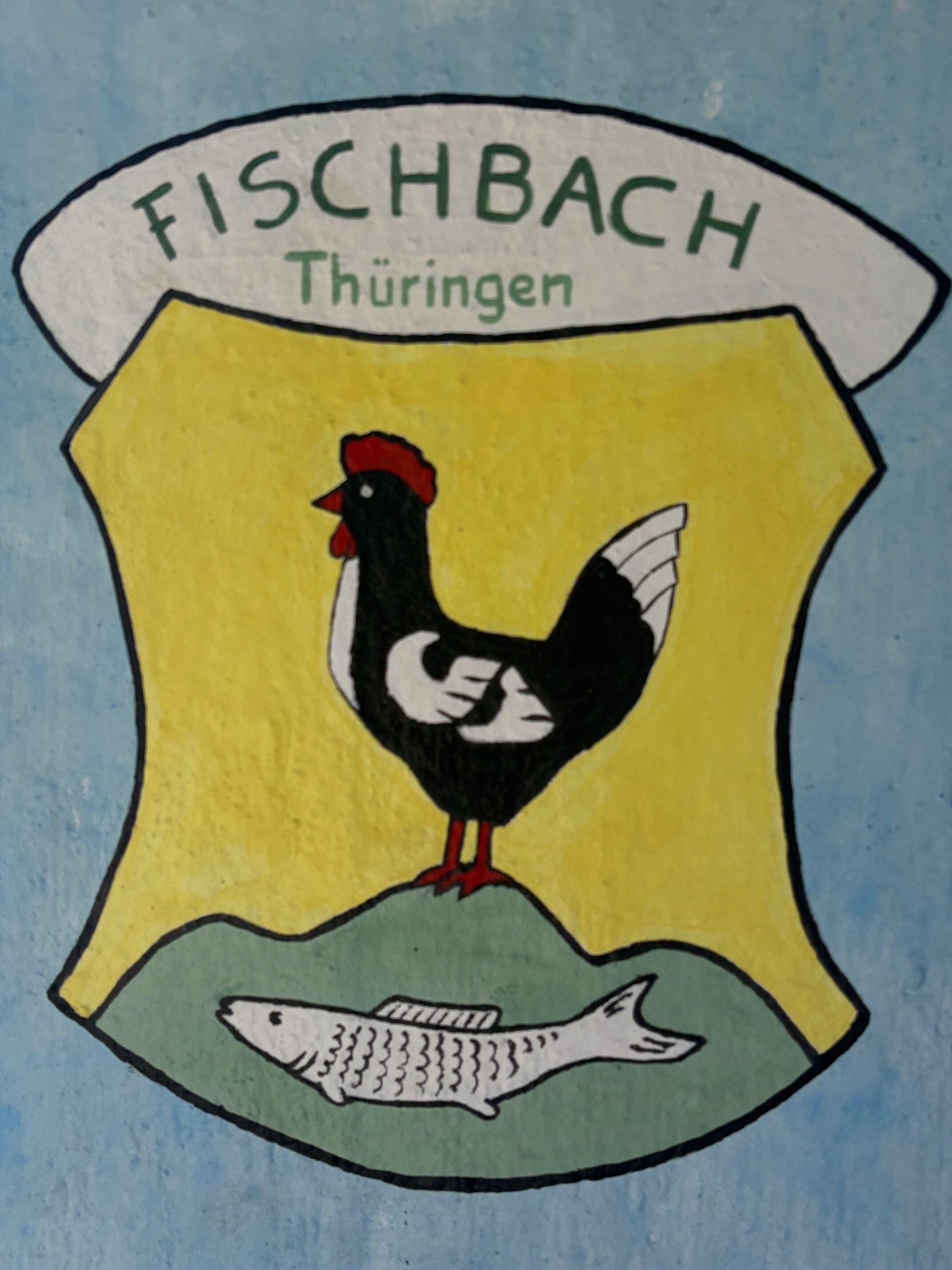 Ein Wappen mit einem Hahn und einem Fisch, mit der Aufschrift „FISCHBACH Thüringen“.