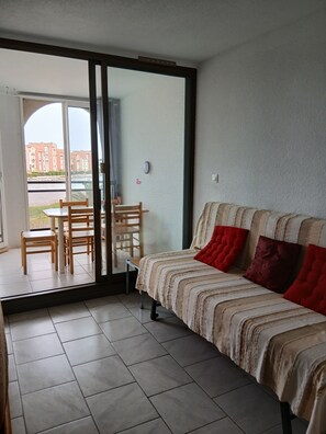 A room with a bed, a table with chairs, and a sliding glass door leading to an outdoor area. - T2 30m2 top floor 3 to 4 sleeps quiet residence (Le Barcarès)
